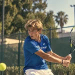 Tennis player hitting a forehand on a hard court during an in-season sports program in Italy