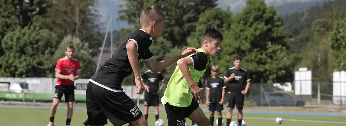 Two young soccer players fighting for the ball during a training match at Champions' Camp in Italy