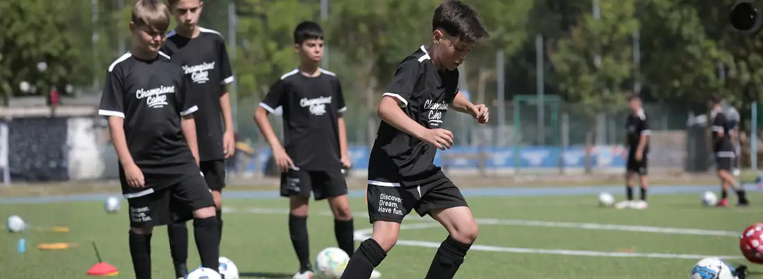 Young soccer player dribbling through cones during a Champions' Camp summer training session in Italy